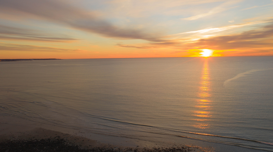Sun setting over a calm sea horizon